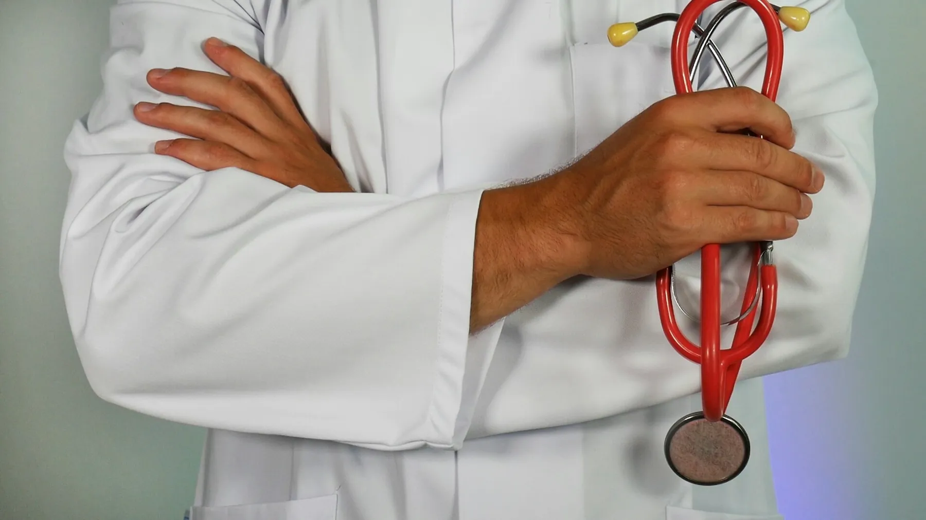 Detalhe de médico de jaleco segurando o estetoscópio